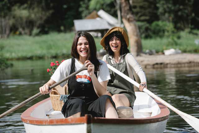 Photo de deux femmes souriant sur une barque en train de ramer