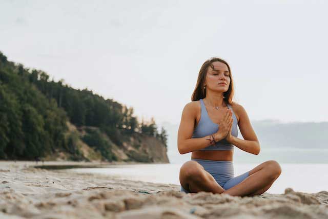 Photo d'une femme faisant du yoga sur une plage en bord de lac