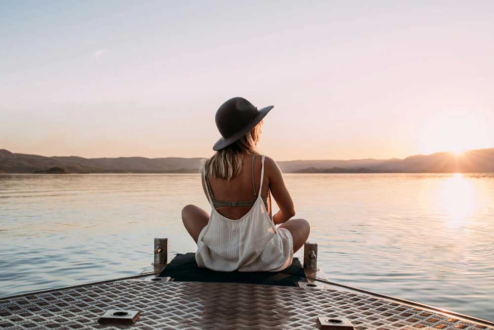 Femme assise sur un ponton à la poursuite de ses rêves